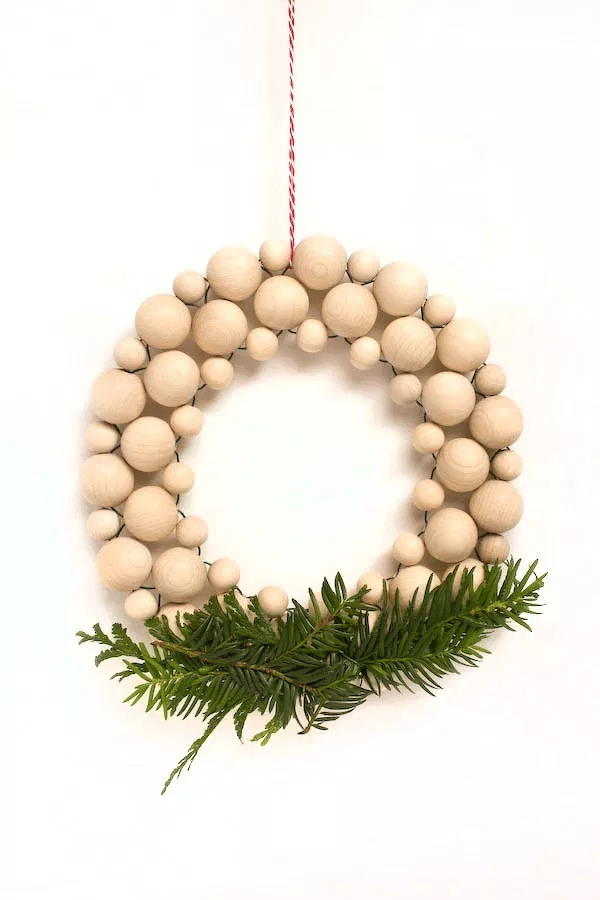 Minimalistický adventní věnec na dveře z dřevěných koulí v severském stylu.